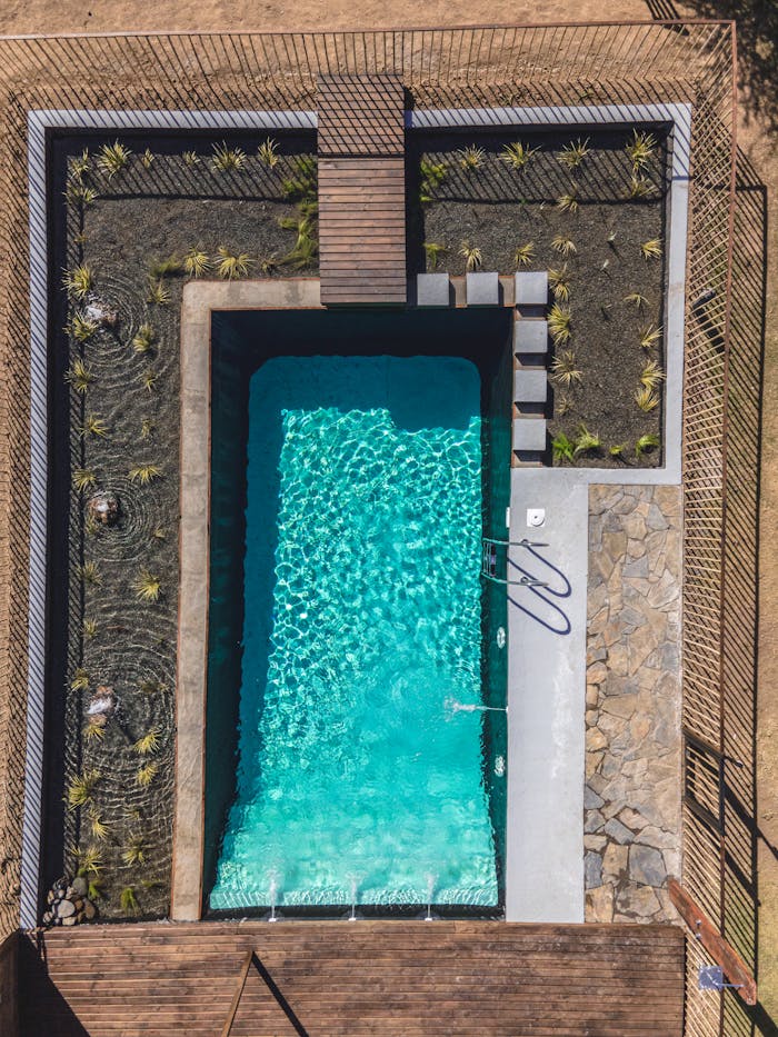 Aerial view of a modern rectangular swimming pool with surrounding landscape architecture.